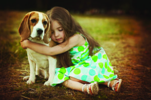 little girl is holding dog outdoors